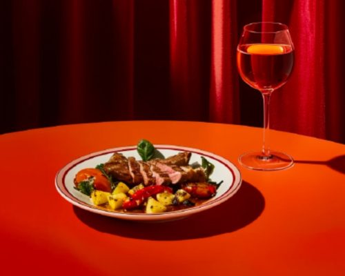 Plato y copa sobre mesa con mantel rojo