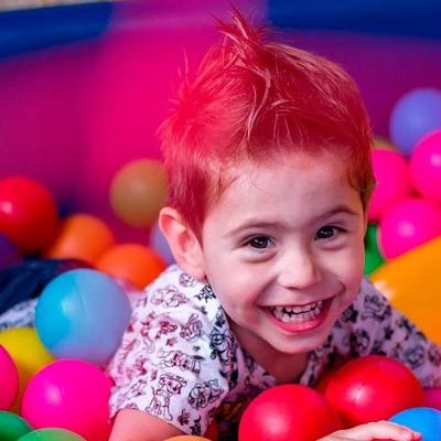 Niño sonriendo en piscina de pelotas de colores plásticas