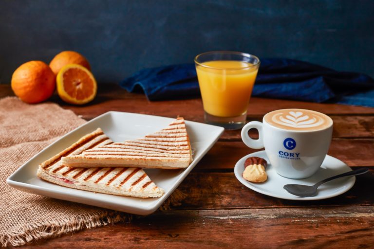 Un desayuno con tostadas, una taza de café y un jugo de naranja
