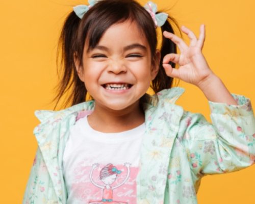 Niña sonriendo con un fondo amarillo