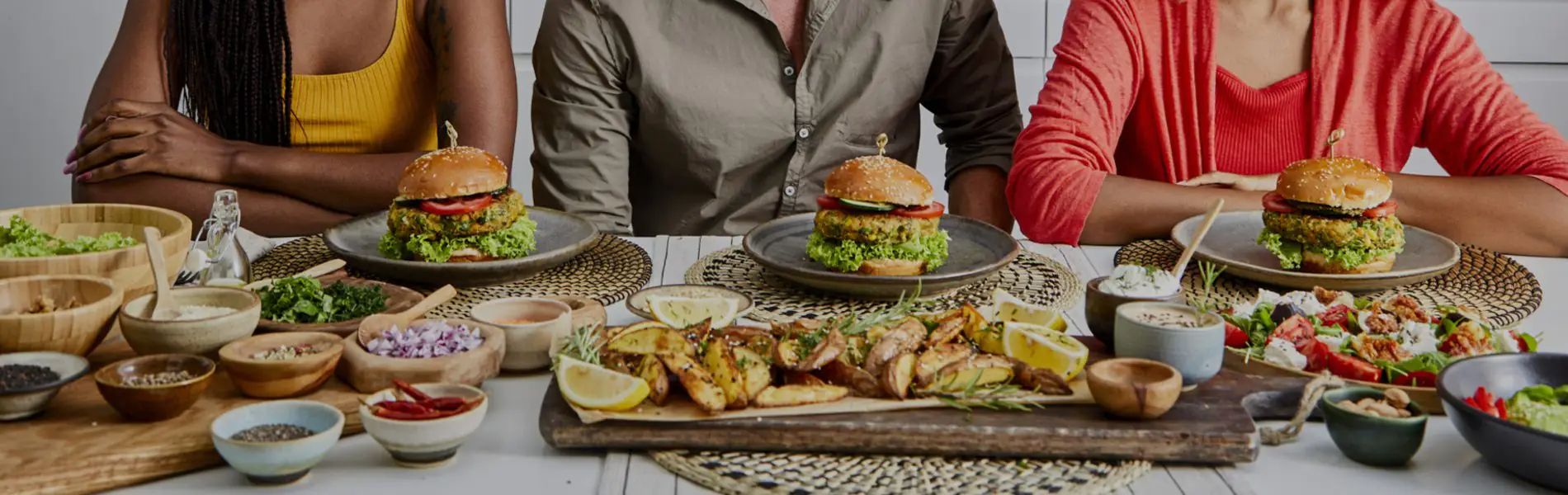 Personas en una mesa con hamburguesas y papas fritas
